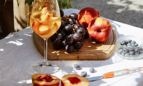 a board of fruit and a glass of wine